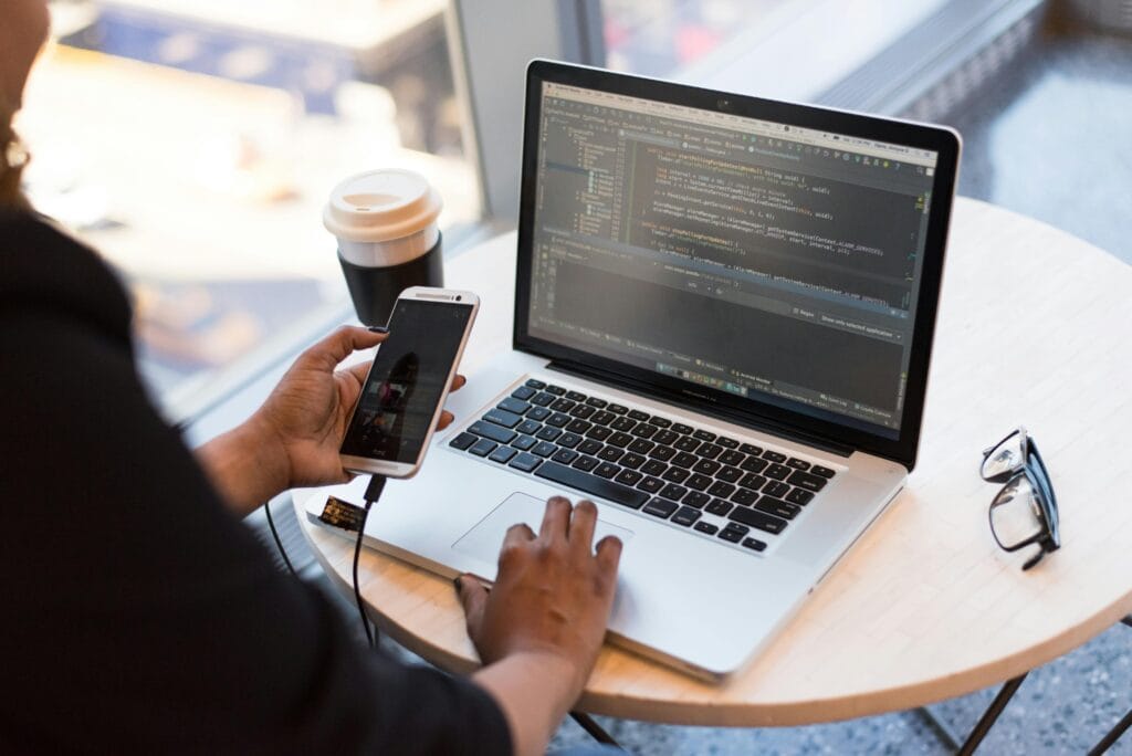pexels-photo-1181244-1181244 Person Holding Smartphone while using Laptop